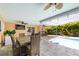 Beautiful covered patio with an outdoor dining area, overlooking the sparkling pool and lush backyard at 9591 Commodore Dr, Seminole, FL 33776