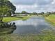 Scenic view of a pond surrounded by lush greenery and mature trees in a residential community at 9591 Commodore Dr, Seminole, FL 33776