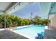 Refreshing pool with a sun lounger, covered patio, and privacy landscaping at 9591 Commodore Dr, Seminole, FL 33776
