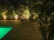 Outdoor patio features a pool with lighting and lounge chairs surrounded by lush landscaping at 9591 Commodore Dr, Seminole, FL 33776