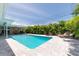 Stunning pool area with lounge chairs, cornhole, lush tropical landscaping and covered patio at 9591 Commodore Dr, Seminole, FL 33776