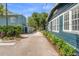Charming blue home with white-trim windows and lush greenery along the driveway at 100 E Fern St, Tampa, FL 33604