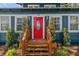 Close-up of the red front door with an oval glass window, surrounded by lush green shrubbery at 100 E Fern St, Tampa, FL 33604