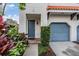 Close up of front entrance, showing blue door, lush landscaping and portion of blue garage at 102 S Moody Ave # 1, Tampa, FL 33609