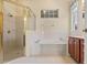 Bright bathroom with tiled floors, soaking tub, and glass shower with gold trim at 1111 Jasmine Creek Ct, Sun City Center, FL 33573