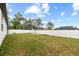 A large backyard with green grass, a grill on a patio, and a tall white fence for privacy at 11123 Thornberry Dr, Spring Hill, FL 34609