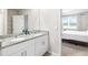 Bathroom featuring double sinks, white cabinets, and a granite countertop adjacent to bedroom at 11123 Thornberry Dr, Spring Hill, FL 34609