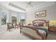 Well-lit bedroom featuring a decorative tray ceiling, ceiling fan, and cozy seating area near the bright windows at 11354 Callisia Dr, Odessa, FL 33556