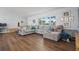Inviting living room with a gray sectional sofa, wood floors, and large windows providing natural light at 11720 80Th Ave, Seminole, FL 33772