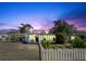 Charming single-story home with a well-manicured lawn and white picket fence at sunset at 1200 47Th St N, St Petersburg, FL 33713