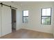 Bright bedroom featuring wood floors, two windows, and modern sliding barn door to ensuite bathroom at 1218 E Kay St # 21, Tampa, FL 33602