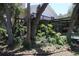 Charming backyard featuring a deck, stairs, covered patio, mature trees, and lush landscaping around the pool at 12929 Sugar Creek Blvd, Hudson, FL 34669