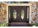 Elegant front door with decorative glass panels, complemented by stone accents and outdoor lighting at 12929 Sugar Creek Blvd, Hudson, FL 34669