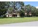 Exterior view of garage with a vehicle inside on a large grassy lawn with mature trees and an American flag at 12929 Sugar Creek Blvd, Hudson, FL 34669