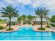Stunning community pool with palm trees, sun loungers and building with covered seating area at 13311 Dorado Shores Ave, Riverview, FL 33579