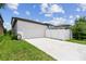 Two car garage and driveway featuring lush green grass, and a white fence at 13311 Dorado Shores Ave, Riverview, FL 33579