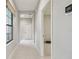 Hallway with neutral walls, white trim and modern white tile flooring leads to a bright living space at 13311 Dorado Shores Ave, Riverview, FL 33579