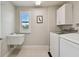 Functional laundry room with sink, washer, dryer, and natural light at 13311 Dorado Shores Ave, Riverview, FL 33579