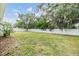 Spacious backyard featuring green grass, a white fence, and mature trees, perfect for outdoor activities at 13814 Harvestwood Ln, Riverview, FL 33569