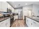 Modern kitchen boasts stainless steel appliances, white cabinets, and sleek countertops with wood flooring at 13814 Harvestwood Ln, Riverview, FL 33569