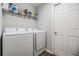 Functional laundry room with modern washer and dryer units and storage shelves at 13814 Harvestwood Ln, Riverview, FL 33569
