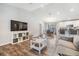 Bright living room featuring wood floors, a large TV, and an open floor plan to dining and kitchen areas at 13814 Harvestwood Ln, Riverview, FL 33569