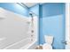 Bright bathroom featuring a white tiled shower and a white toilet with a blue accent wall at 14135 Arbor Pines Dr, Riverview, FL 33579