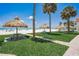 Beach scene with grass, picnic tables, huts, and palm trees at 17500 Gulf Blvd # 407, Redington Shores, FL 33708