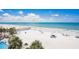 A view of the beachside property with a white sand beach, clear ocean water, and tropical palm trees at 17500 Gulf Blvd # 407, Redington Shores, FL 33708