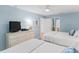 Bedroom with ceiling fan, two beds and dresser with TV leading to the ensuite bathroom at 17500 Gulf Blvd # 407, Redington Shores, FL 33708