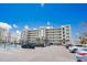 Exterior view of building featuring many floors of condos with a full parking lot and tennis court at 17500 Gulf Blvd # 407, Redington Shores, FL 33708