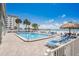 Swimming pool and beach with palm trees and beach lounge chairs at 17500 Gulf Blvd # 407, Redington Shores, FL 33708