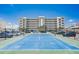 Tennis court featuring a view of the condo building, parking, and blue sky at 17500 Gulf Blvd # 407, Redington Shores, FL 33708