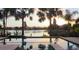 Backyard pool offering breathtaking sunset water views framed by palm trees, merging relaxation with stunning scenery at 18036 Java Isle Dr, Tampa, FL 33647