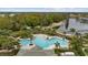 Aerial view of a community pool featuring palm trees, lounge chairs, and lake access with a sandy beach area at 18036 Java Isle Dr, Tampa, FL 33647