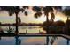 Sparkling pool with a beautiful sunset view across the lake framed by palm trees offering relaxation and stunning scenery at 18036 Java Isle Dr, Tampa, FL 33647