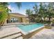 Sparkling pool with travertine tile, waterfall feature, and covered patio, creating a relaxing outdoor oasis at 18036 Java Isle Dr, Tampa, FL 33647