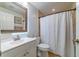 Clean bathroom with white vanity, granite countertop, a framed mirror with LED lighting, and a shower with curtain at 18504 Country Crest Pl, Tampa, FL 33647