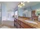 Bright bathroom features a soaking tub, granite countertop, and a large mirror with decorative light fixtures at 18504 Country Crest Pl, Tampa, FL 33647