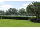 Tennis courts with fencing and manicured hedges surrounding a green lawn at 18504 Country Crest Pl, Tampa, FL 33647