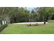 A sand volleyball court and picnic tables on a grassy common area with mature trees providing shade at 18504 Country Crest Pl, Tampa, FL 33647