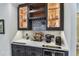 Close-up of a bar area featuring dark cabinetry, wine storage, under-counter refrigerator, and decorative glass backsplash tiles at 200 Skiff Pt # 202, Clearwater Beach, FL 33767