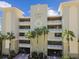 Majestic Point condos exterior featuring a neutral facade, tropical landscaping, and secure gated entrances at 200 Skiff Pt # 202, Clearwater Beach, FL 33767