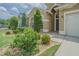 Charming home featuring manicured garden beds, mature shrubbery, and a tiled walkway to the front door at 2124 Rensselaer Dr, Wesley Chapel, FL 33543