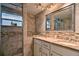 Bright bathroom featuring a double sink vanity, neutral stone tiling, and a shower with glass door at 284 North St, Palm Harbor, FL 34683