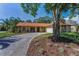 Charming single-story home featuring a stone facade, lush landscaping, and a long driveway leading to an attached garage at 3041 Oak View Dr, Palm Harbor, FL 34684