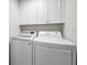 Bright laundry room with washer, dryer, and white cabinets at 3041 Oak View Dr, Palm Harbor, FL 34684