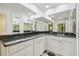 Bathroom area features large mirrors, black countertops, white cabinets and black and white tiled floors at 3105 W San Isidro St, Tampa, FL 33629