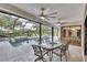 Covered patio with a seating area overlooking the beautiful pool, outdoor waterfall, and lush landscaping at 3207 Hilltop Ln, Largo, FL 33770