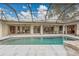 The screened-in pool offers views of the home's patio, landscaping, and rock water feature at 3207 Hilltop Ln, Largo, FL 33770